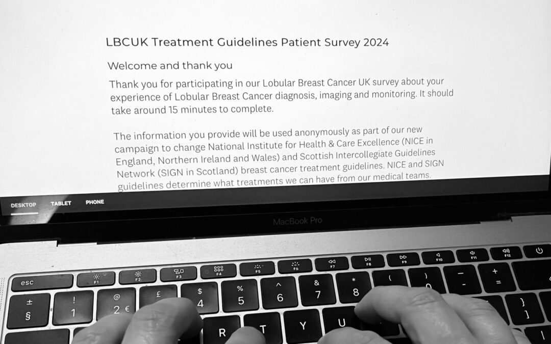 Black and white image of a computer and hands typing responses into an online survey for Lobular Breast Cancer